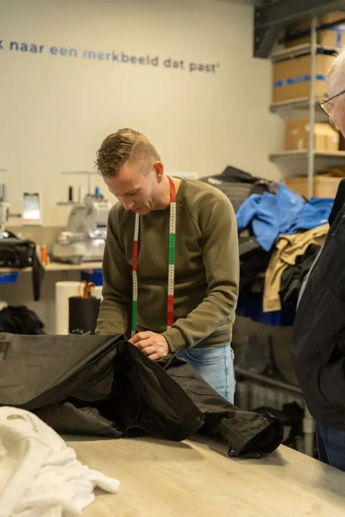 Gerard bij de borduurmachines in het atelier